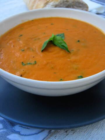 close up of the tomato and basil soup in a white bowl