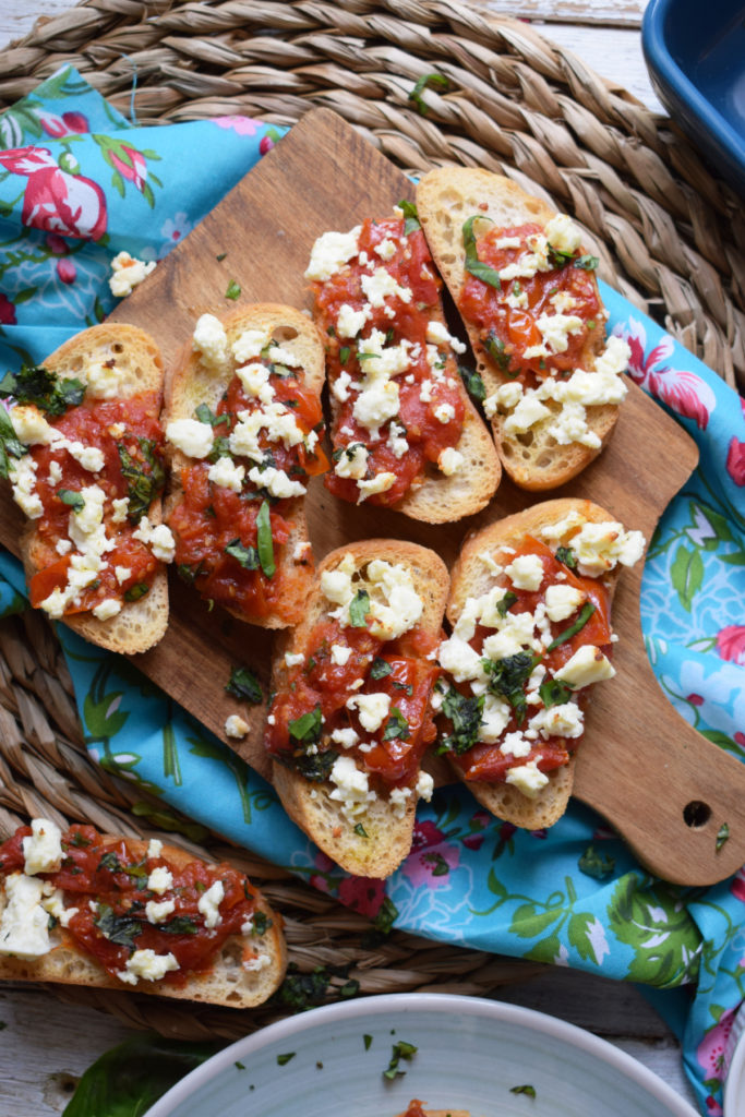 roated tomato and feta bruschatta on a serving board