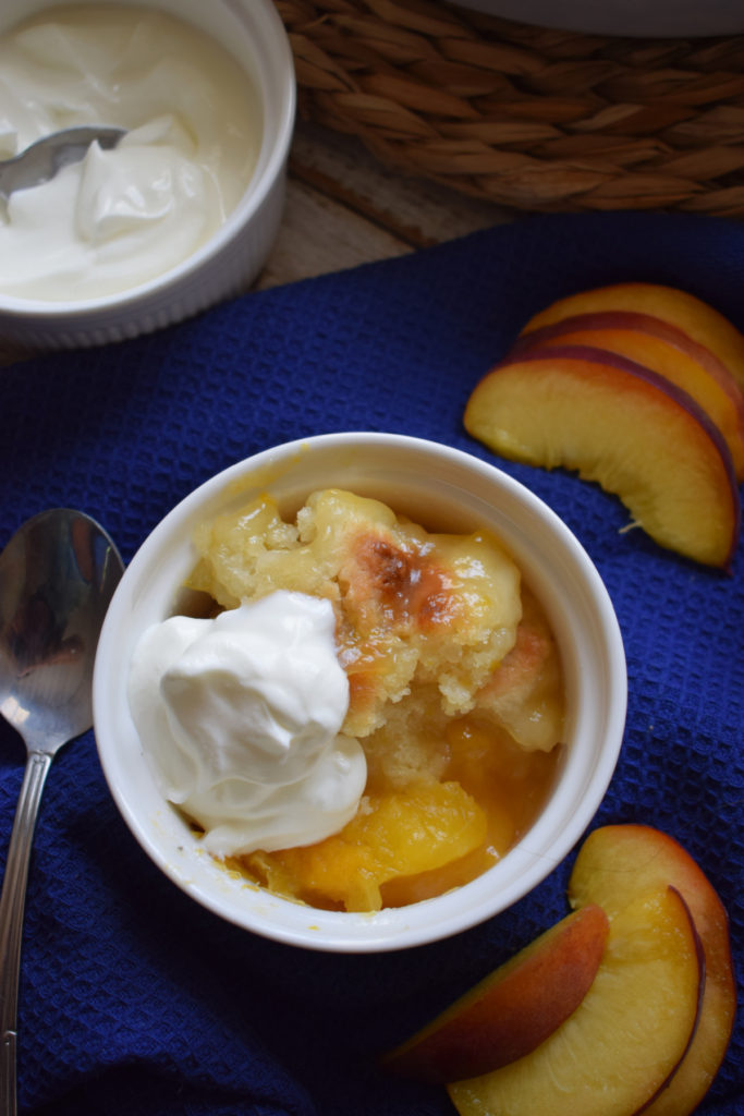 Peach cobbler in a bowl with cream