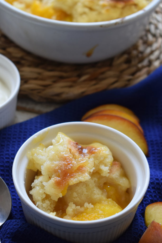 Peach cobbler in a serving dish with a blue tea towel