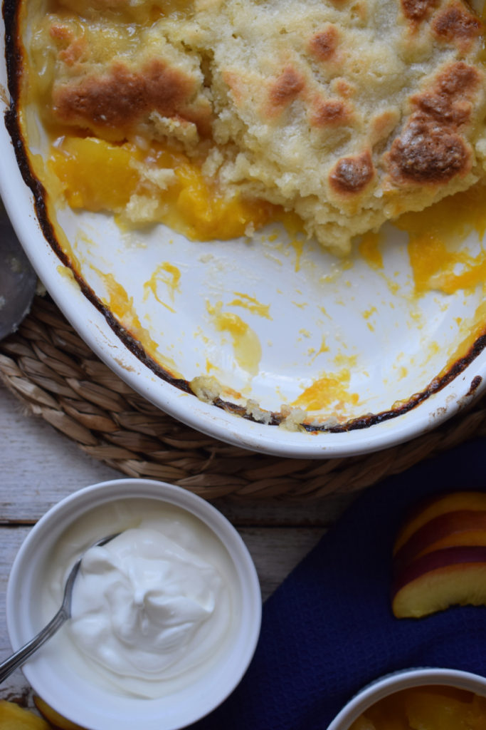 Peach cobbler in a dish with cream on the side