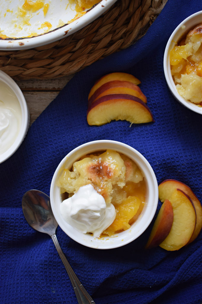 over head view of peach cobbler in a serving dish with fresh peaches