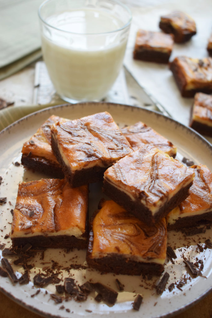 cream cheese brownies on a plate with a glass of milk