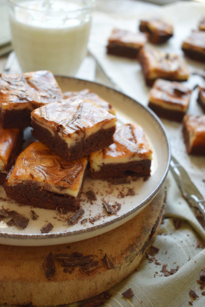 Cream cheese brownies stacked on a plate