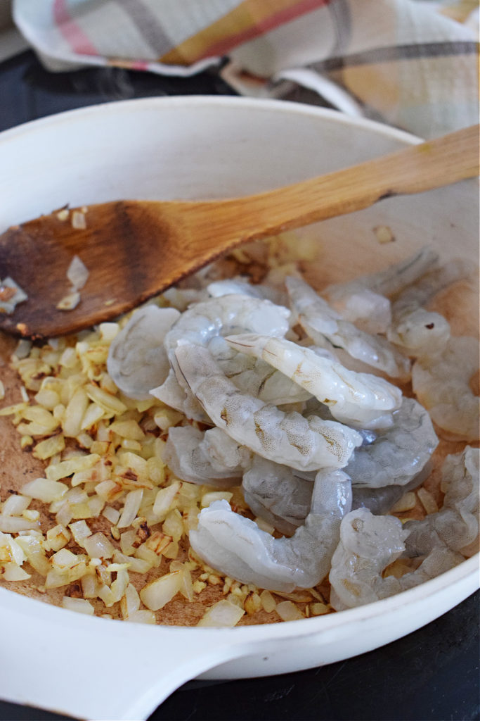 adding shrimp to the pan to cook the teriyaki shrimp and rice