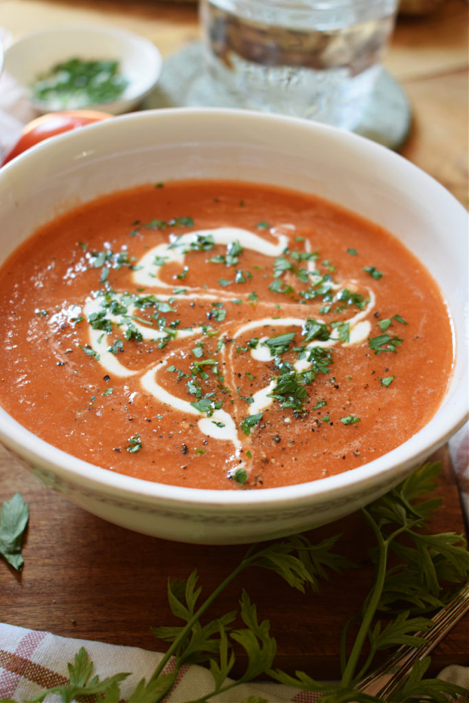 close up of a bowl of tomato soup with fresh cream