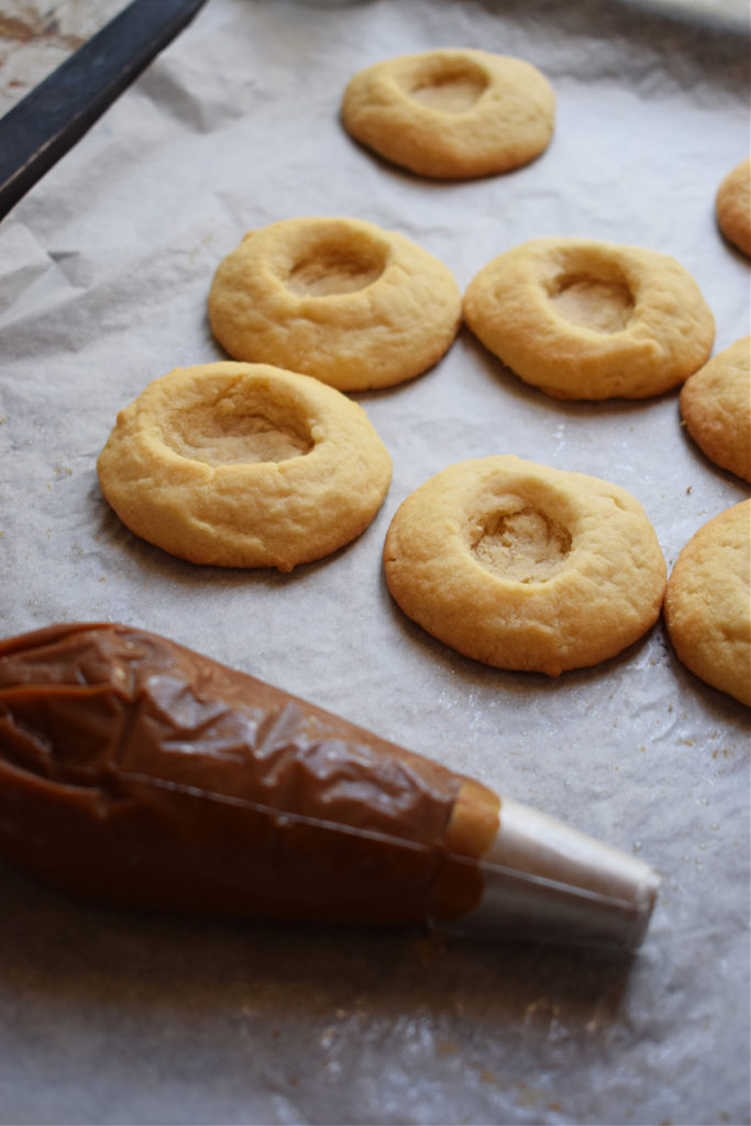 thumbprint cookies on a tray ready to fill with dulce de leche