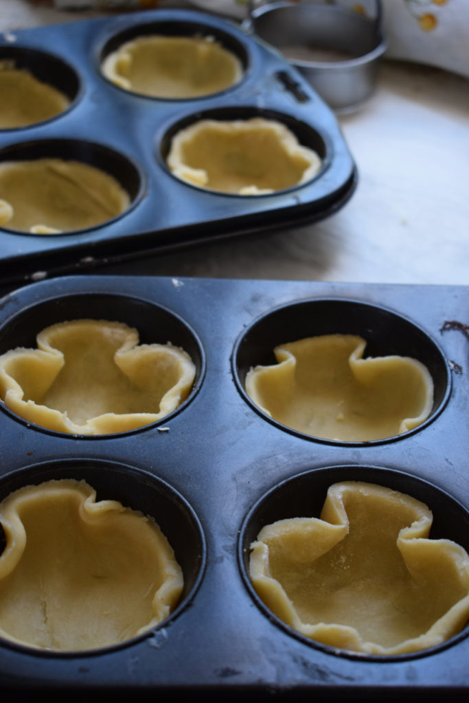 filling muffin tins with pastry to make mini pumpkin pies