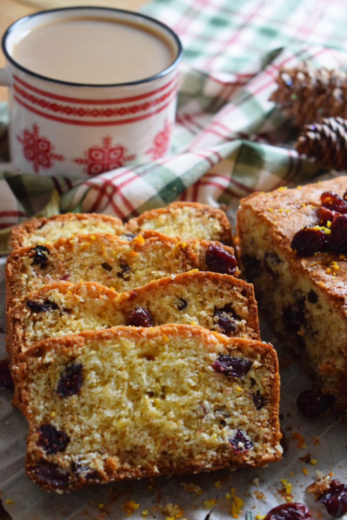 close up of the dried cranberry loaf cake with a cup of coffee