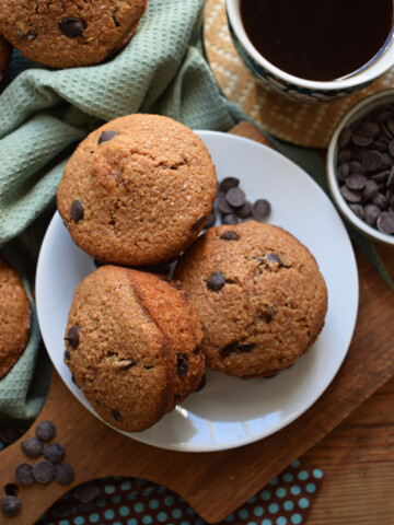 Chocolate chip bran muffins on a plate with a cup of coffee.