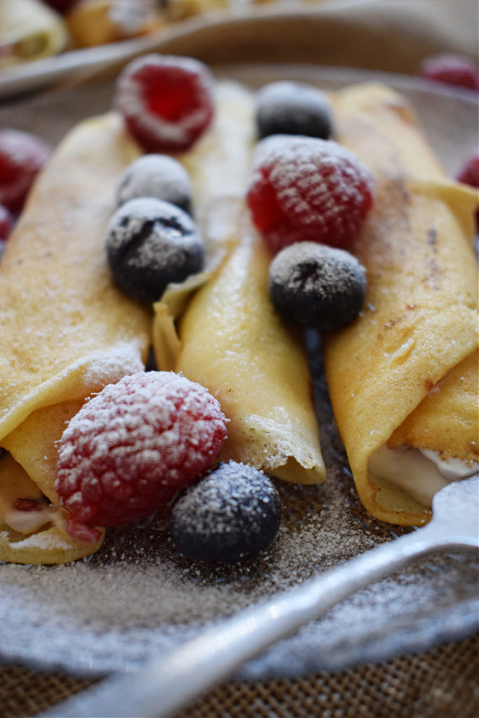 Close up of crepes and berries on a plate.