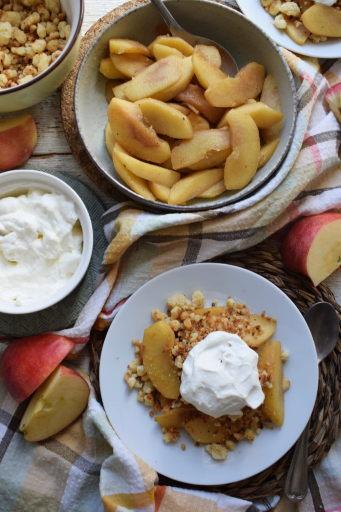 Apple crumbe on a plate and cooked appels in a bowl.