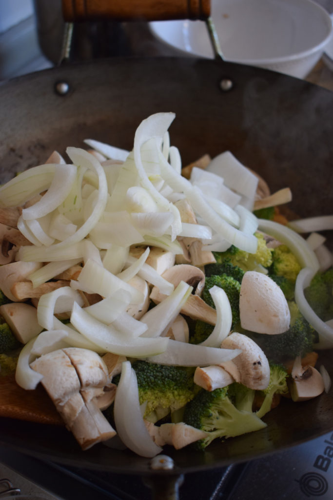Adding vegetables to a wok to make a stir fry.