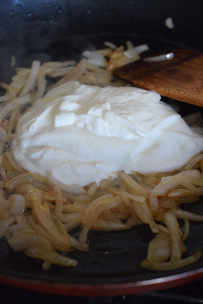 Adding creme fraiche to sauteed onions to make pasta primavera.
