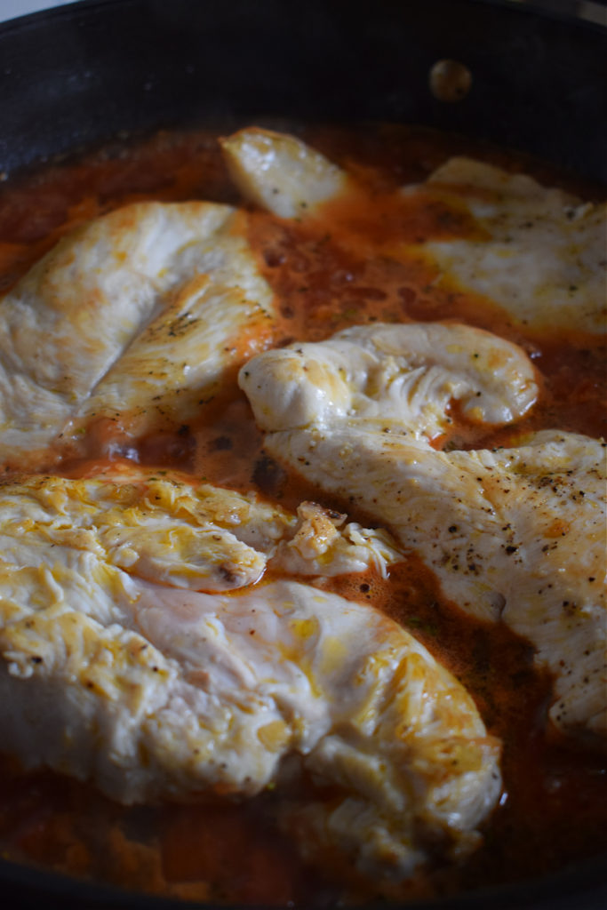 Cooking chicken cutlets in tomato sauce.