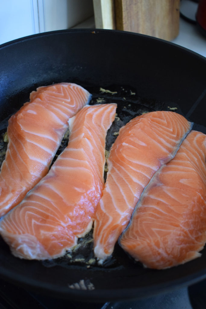 Salmon cooking in a skilet.