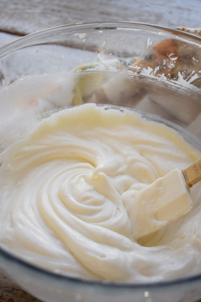 Whipped cream cheese frosting in a glass bowl.