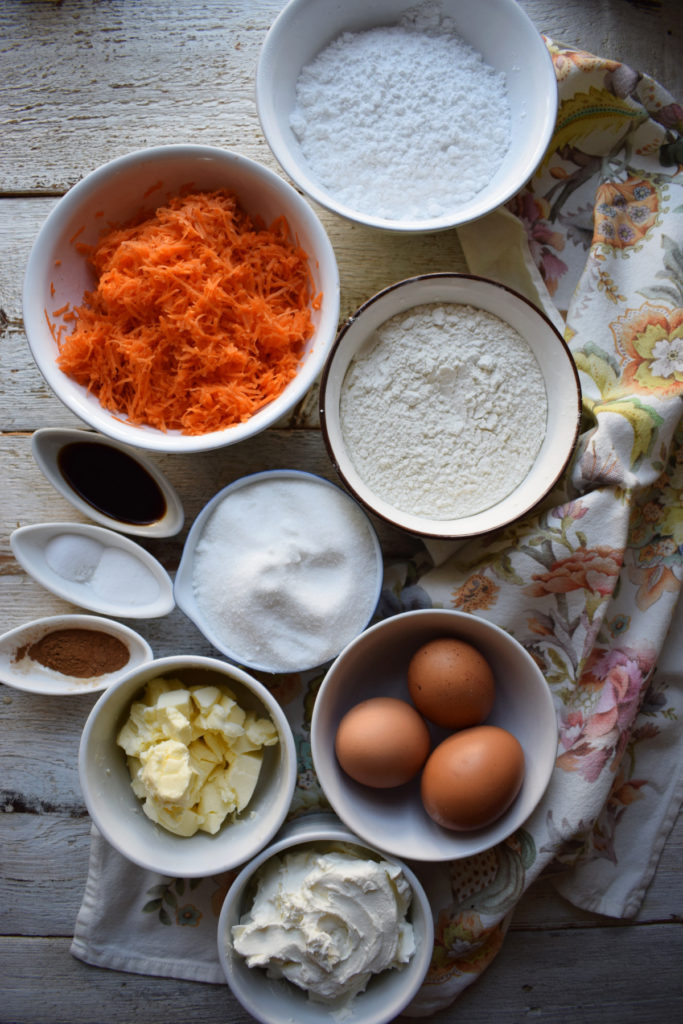 Ingredients to make a carrot loaf cake on a wooden table.