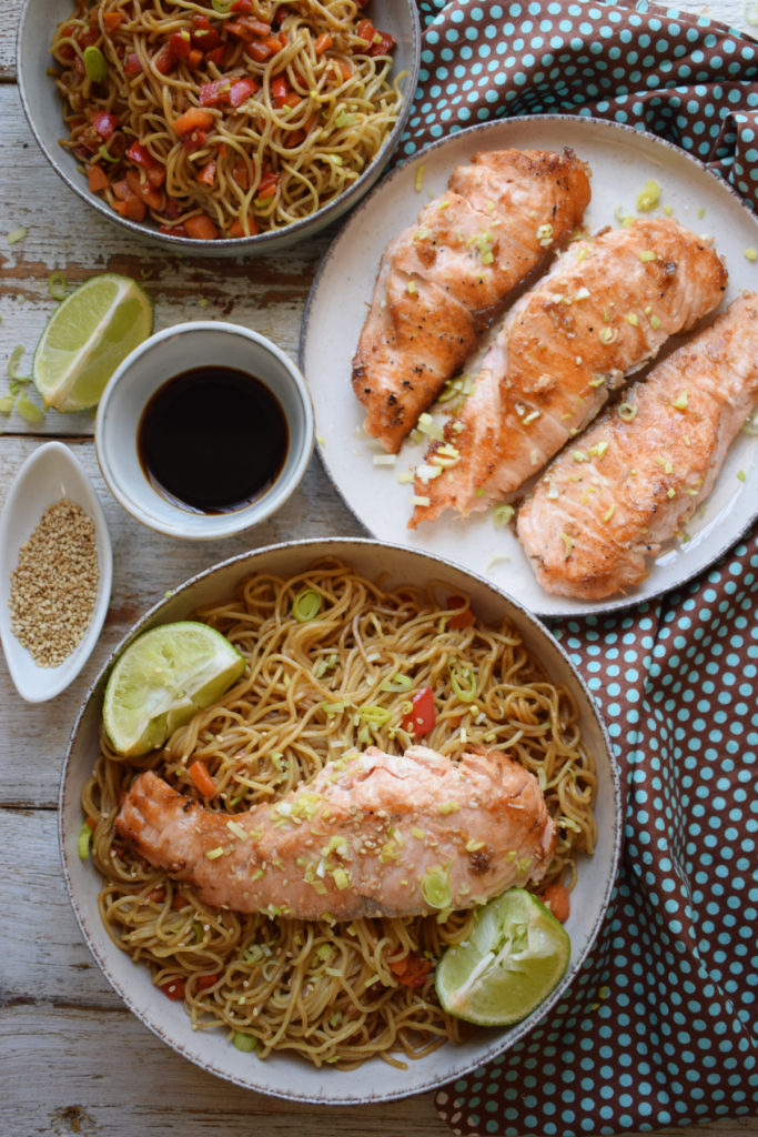 Salmon and Noodles on a white wooden table with teriyaki sauce and sesame seeds.