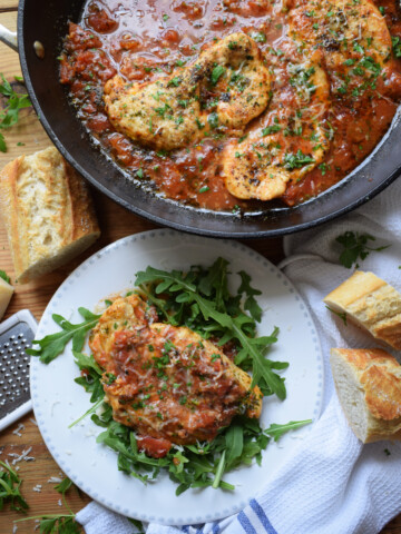 Parmesan and Tomato Skillet Chicken in a serving dish and a portion on a plate.