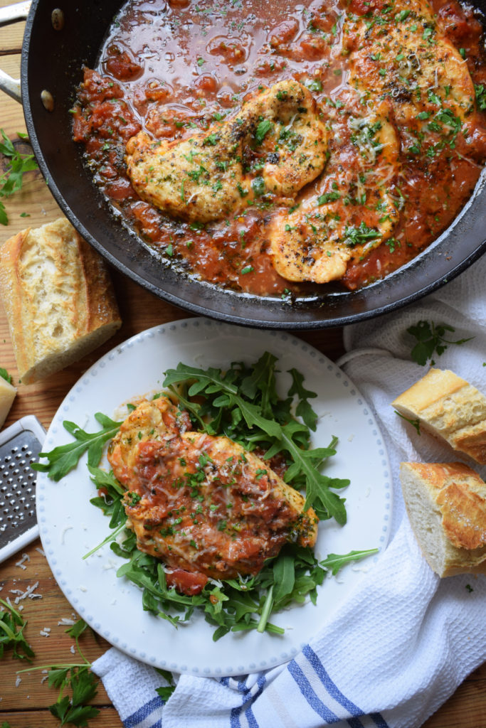 Parmesan and Tomato Skillet Chicken in a serving dish and a portion on a plate.