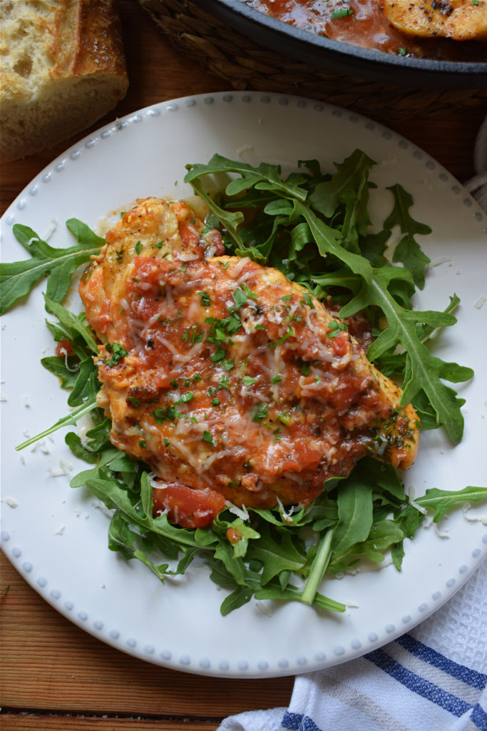 Parmesan chicken on a plate with fresh arugula.