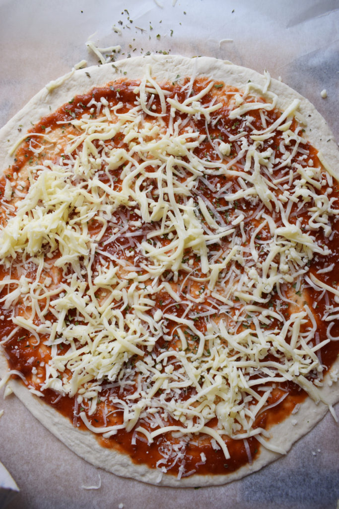 A pizza topped with mozzarella cheese ready to bake.