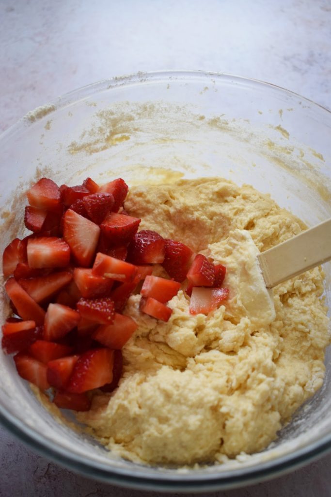 Adding strawberreis to muffin batter.