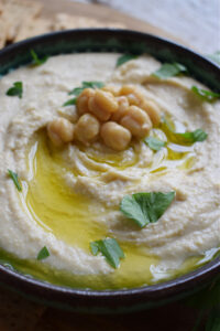 Humms in a bowl with olive oil and chickpeas.