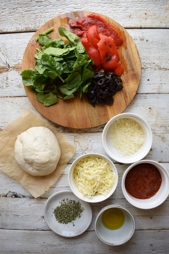 Ingredients on a white board to make a mediterranean style pizza