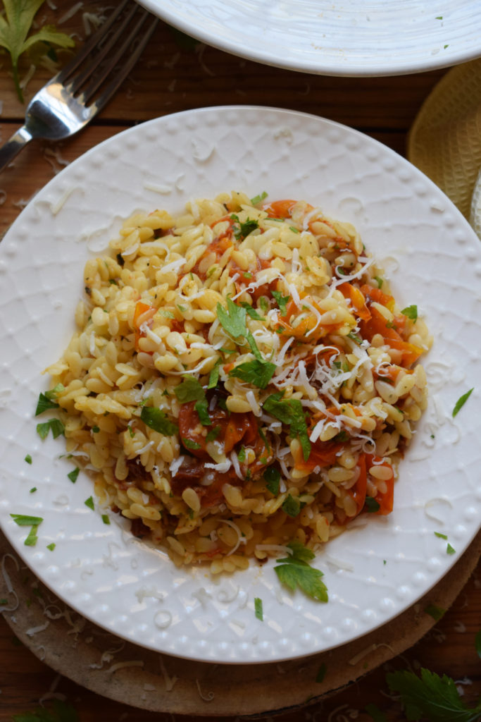 Orzo pasta salad on a plate with a fork.