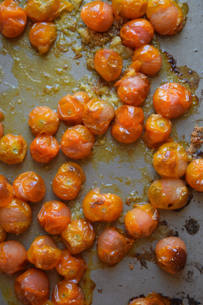 Roasted cherry tomatoes on a baking tray.