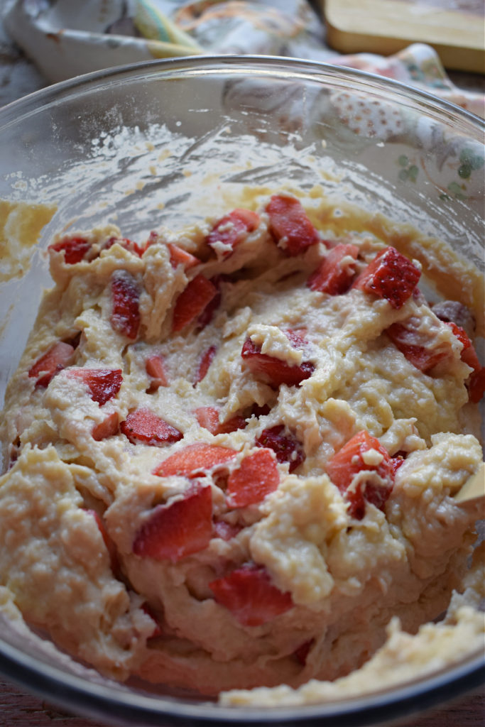 Adding strawberries to batter to make muffins.