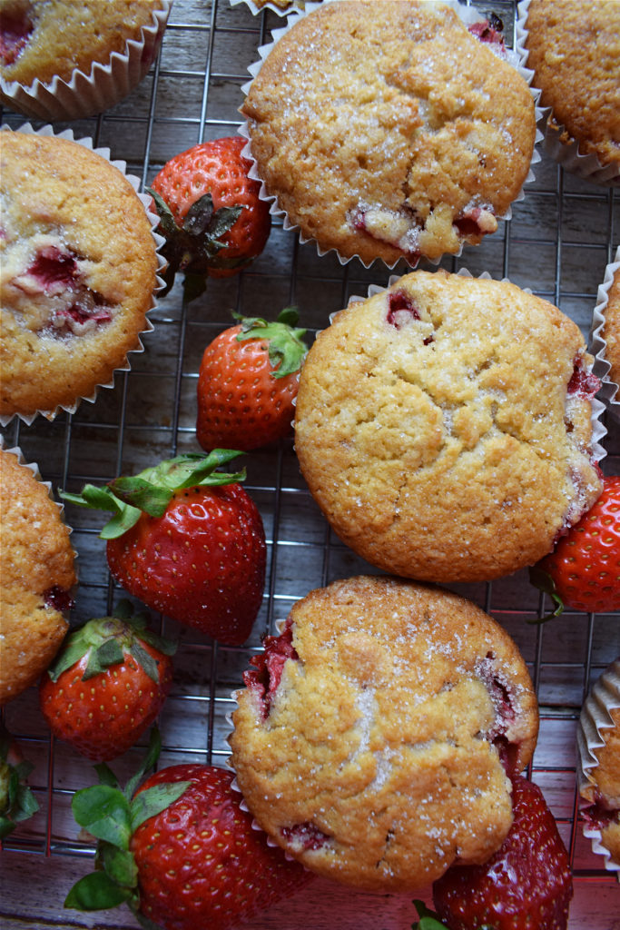 Strawberry shortcake muffins on a baking tray with strawberries.