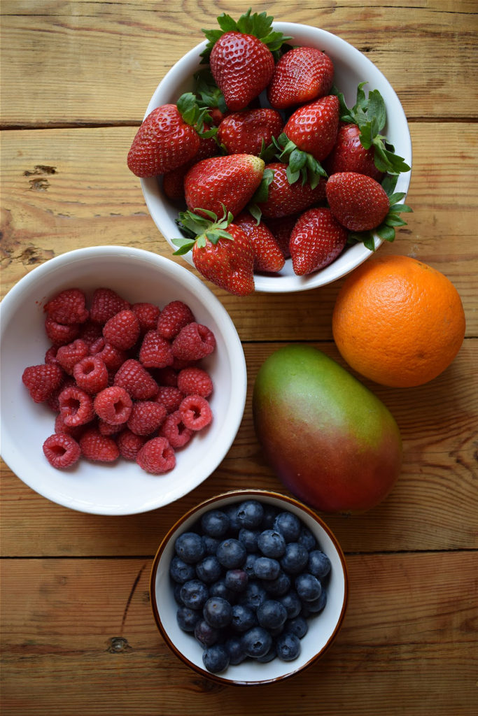 Ingredients to make a summer berry salad on a wooden table.