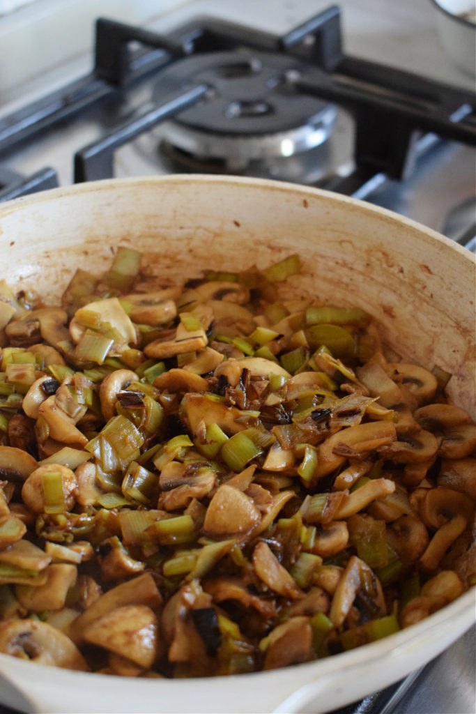 Cooked leeks and mushrooms in a skillet.