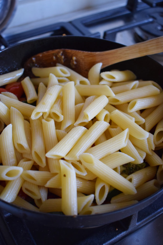 Adding pasta to a skillet.