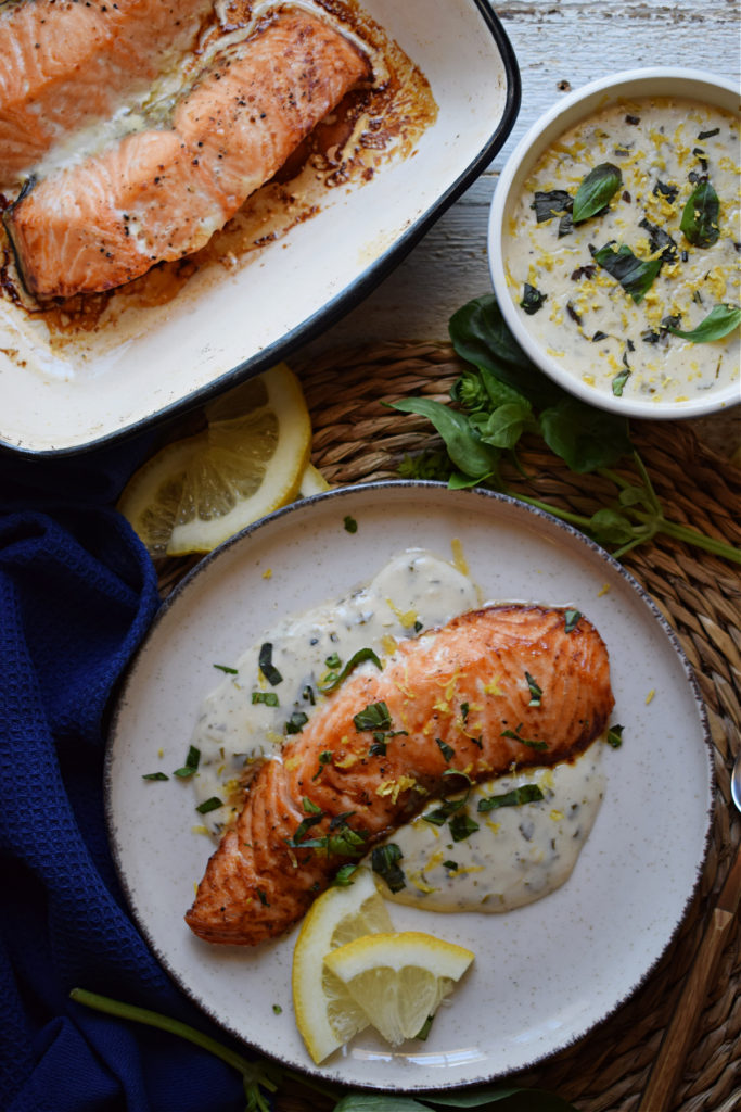 Baked salmon with sauce on a plate and a side of sauce.