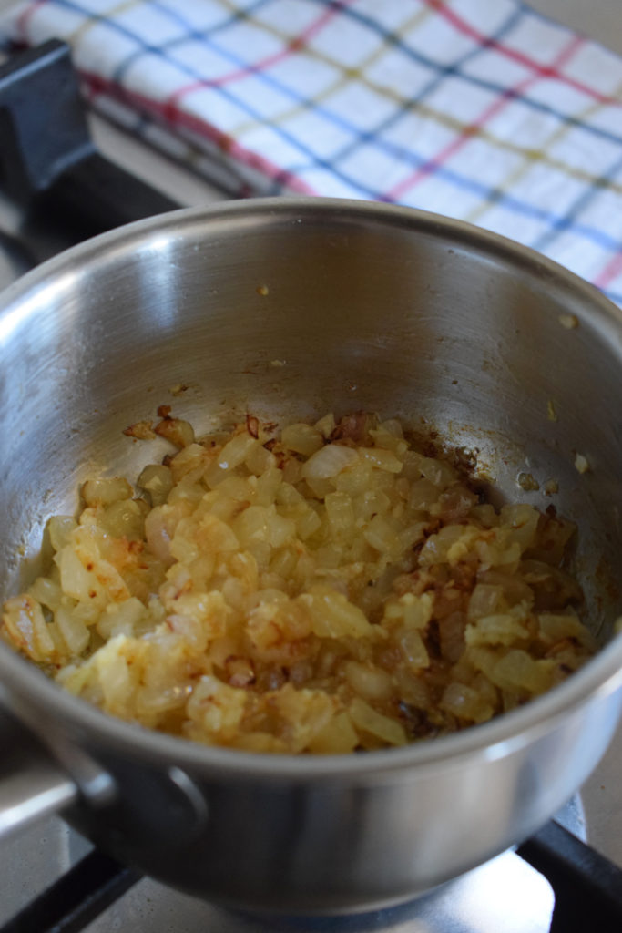 Cooked onions in a small saucepan.