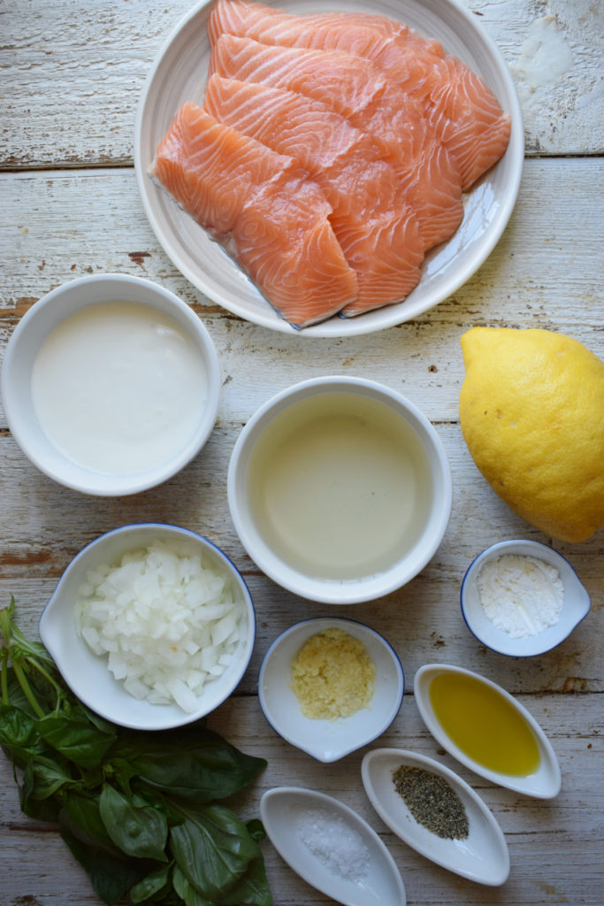 Ingredients on a white table for Baked Salmon with Lemon Basil Cream Sauce