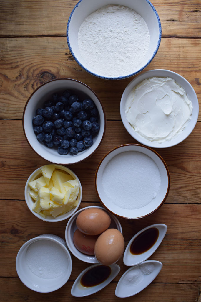 Ingredients on a wooden table to make blueberry cake squares.