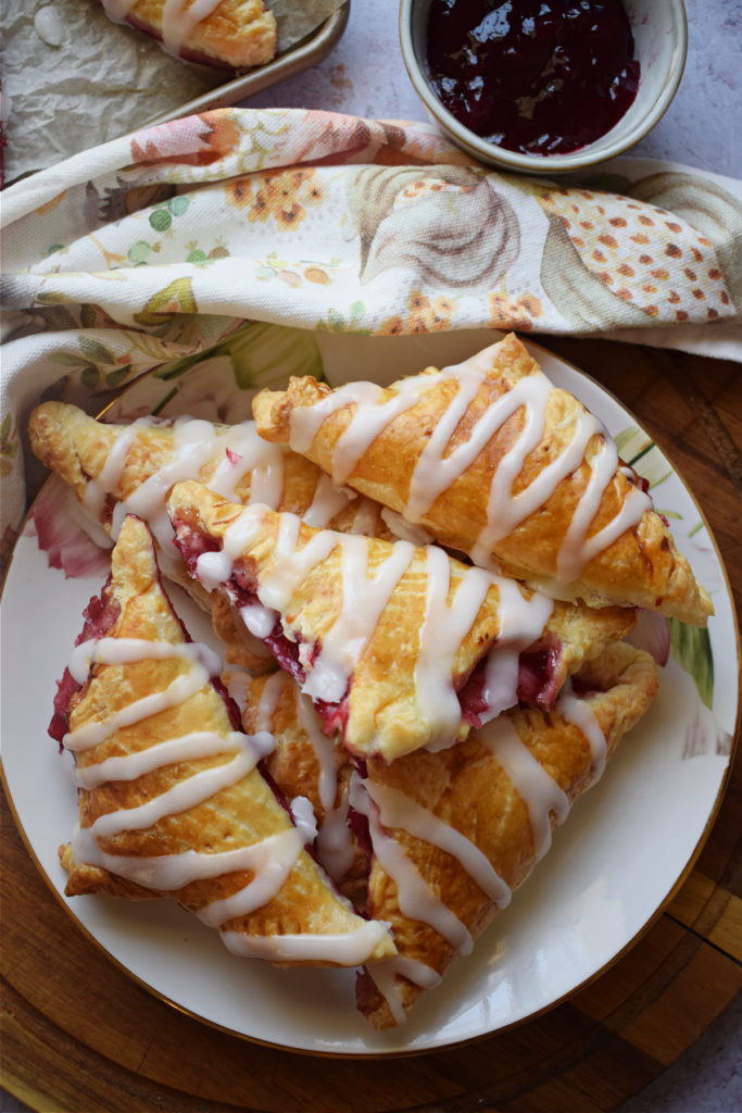 Pastry turnovers on a plate with a bowl of jam.
