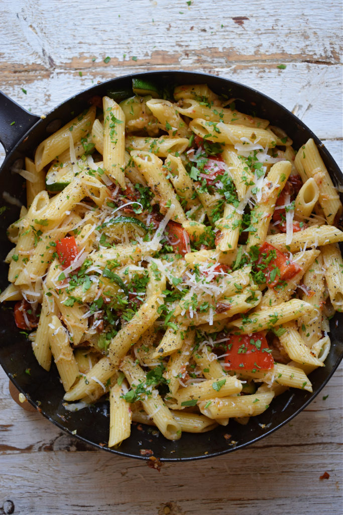 Pasta in a skillet with vegetables.