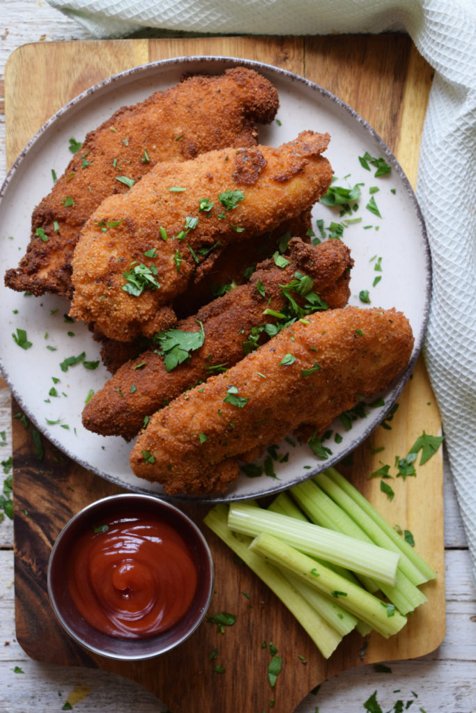 Chicken Tenders on a plate with dipping sauce and celery.