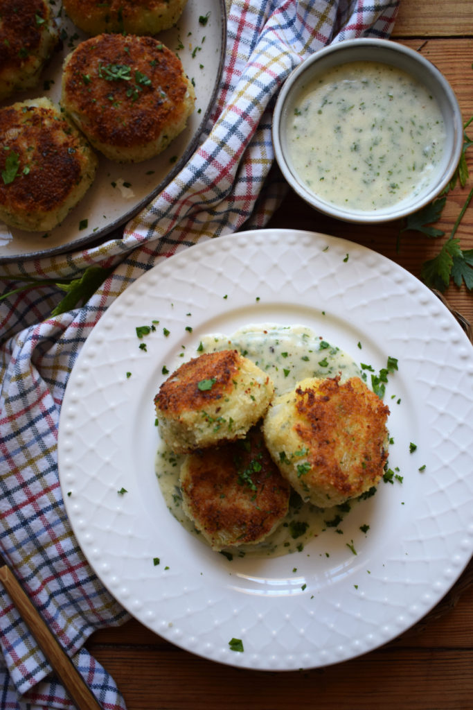 Cod cakes with parsley sauce on a plate.