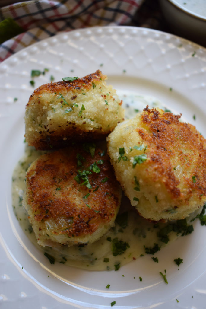 Cod cakes on a plate with a creamy sauce.