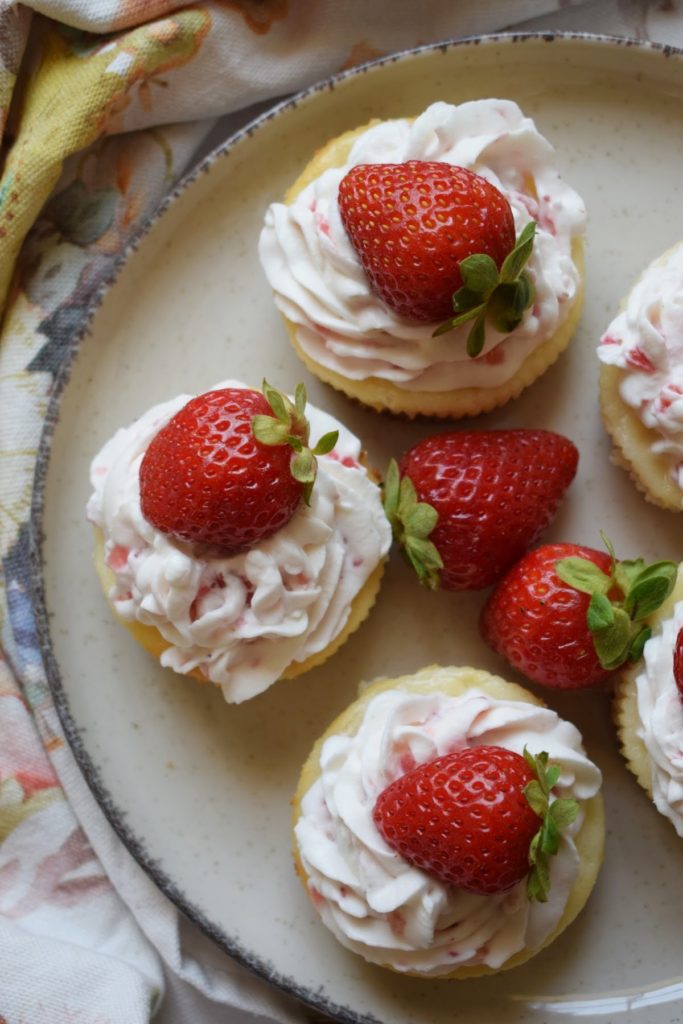 Three mini strawberry cheesecakes on a plate.
