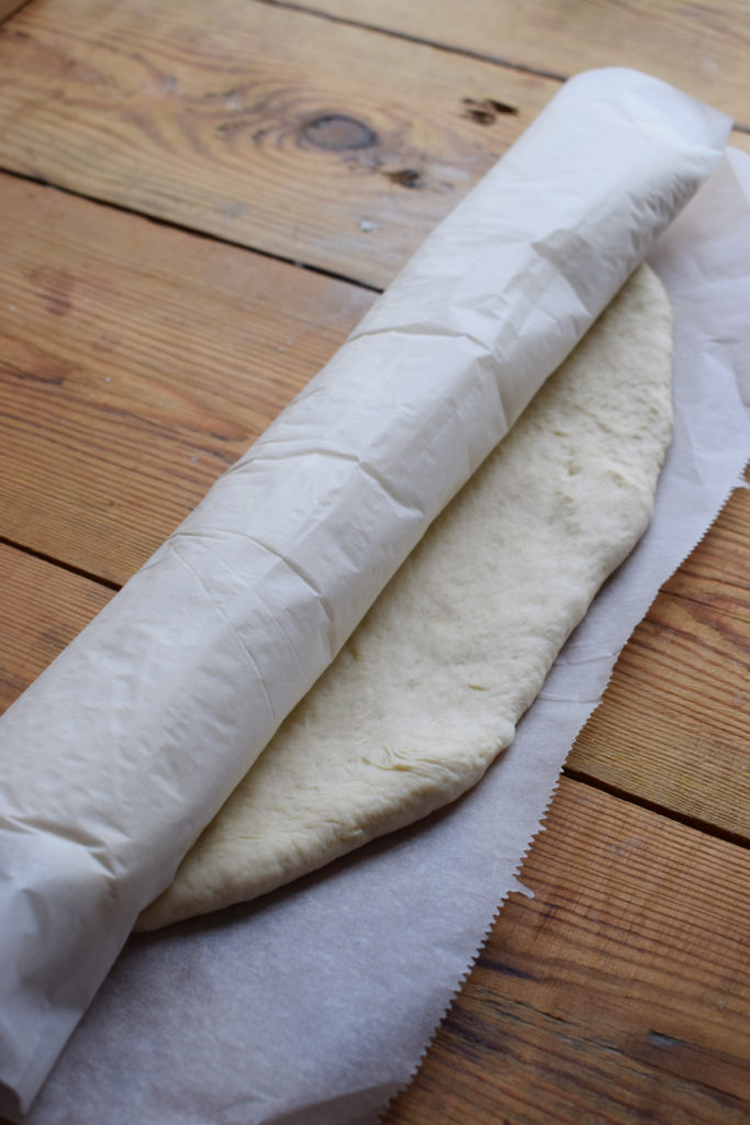 Rolled up pizza dough in parchment paper.