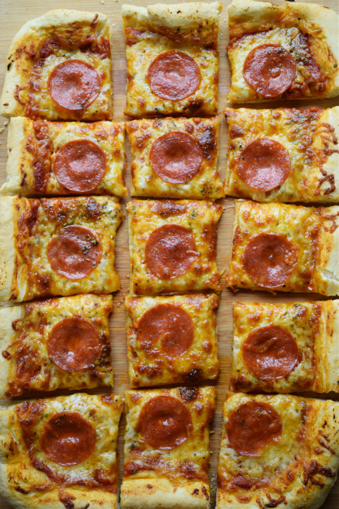 A sheet pan pepperoni pizza cut into 15 equal squares.