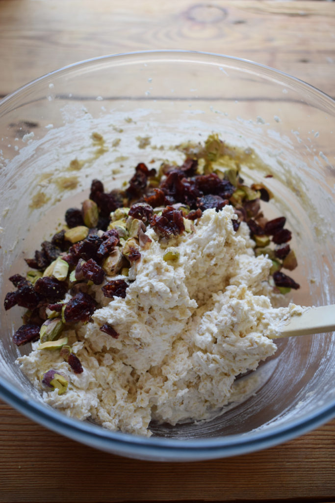 Adding dried cranberries and pistachios to cookie dough.
